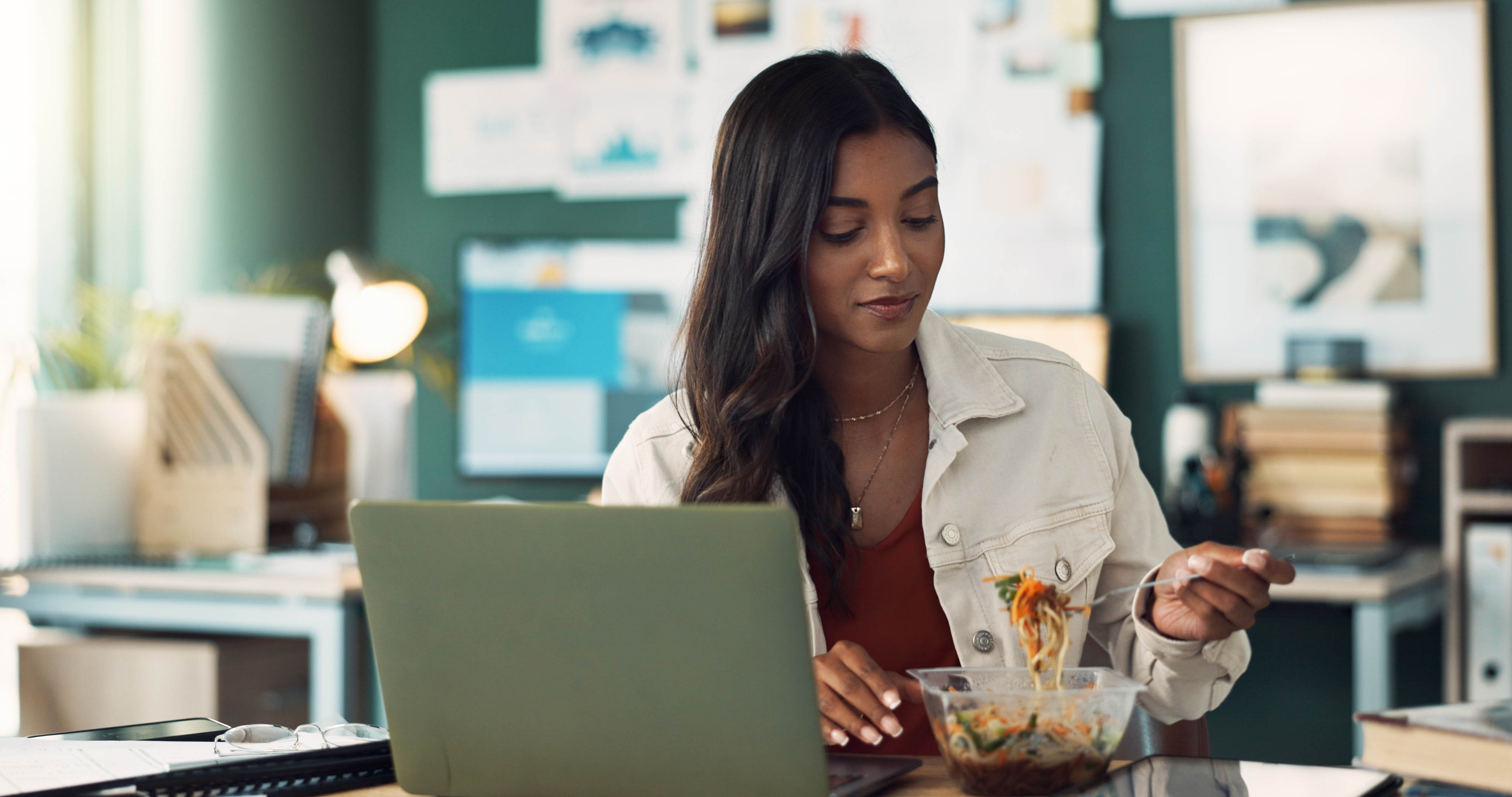 Woman eating her healthy lunch at her desk while at work